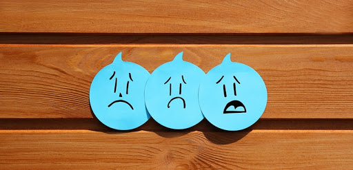 3 blue round stickies with hand drawn sad faces on them