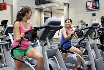 2 female students working out on stationary bikes