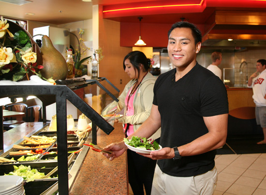 student serving themselves at the salad bar