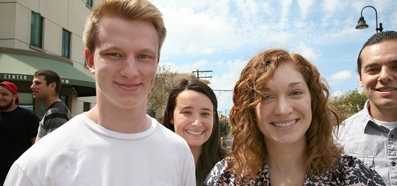 4 students smiling outside of Calpulli building with blue skies