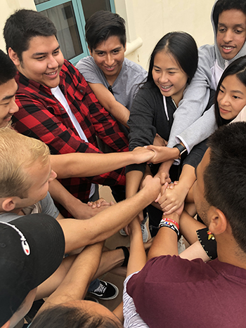 group of students with their hands together in the center