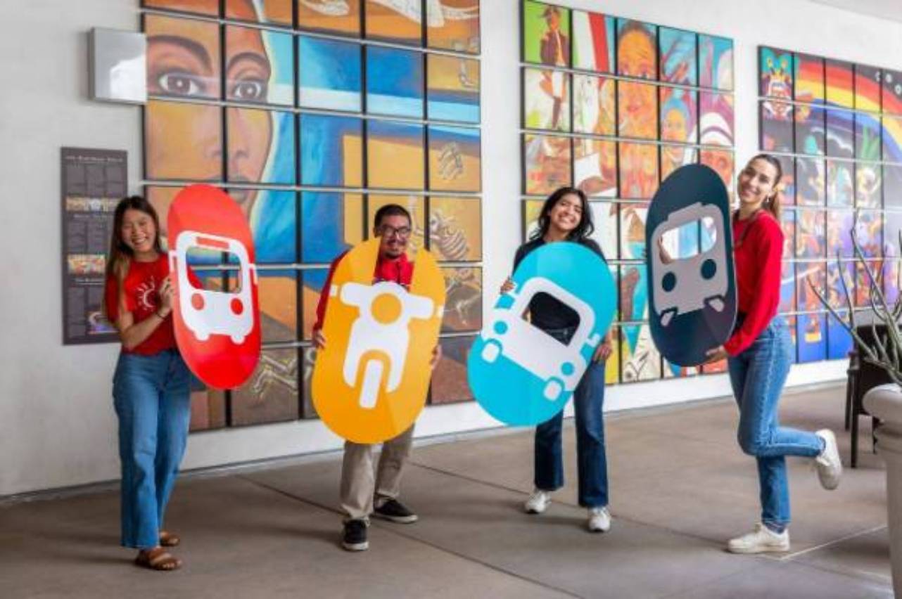 Four students each holding a cardboard cut out of one of the vehicals in the commuter life logo